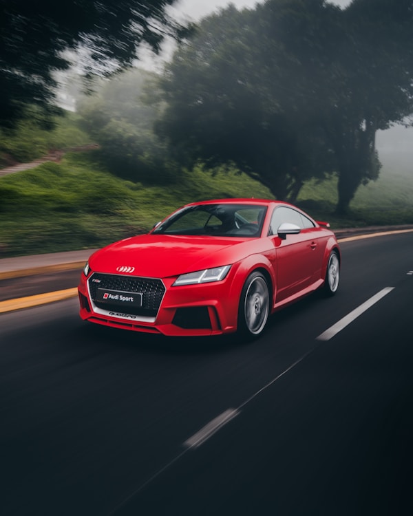 Red coupe on an open road, the kind of everyday driving that shapes an insurance rate